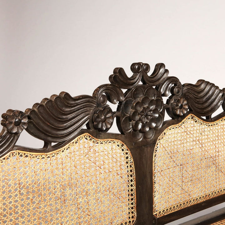 Close-up of carved floral and palmette details on ebony sofa back from Collection EE20 with caned panels