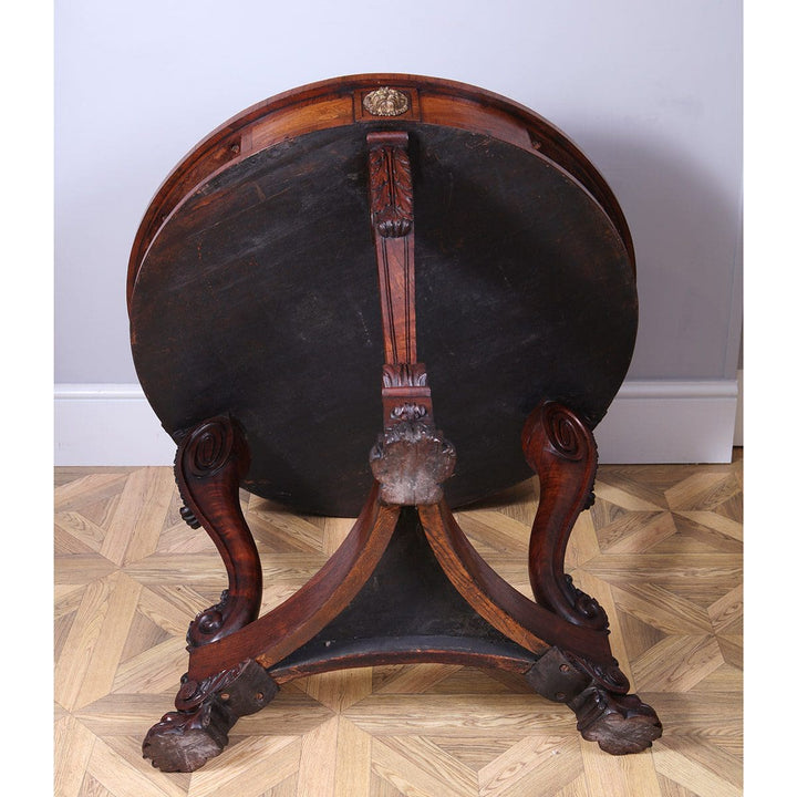 Regency Rosewood Drum Table showing detailed underside with carved scroll legs and claw feet on parquet floor.