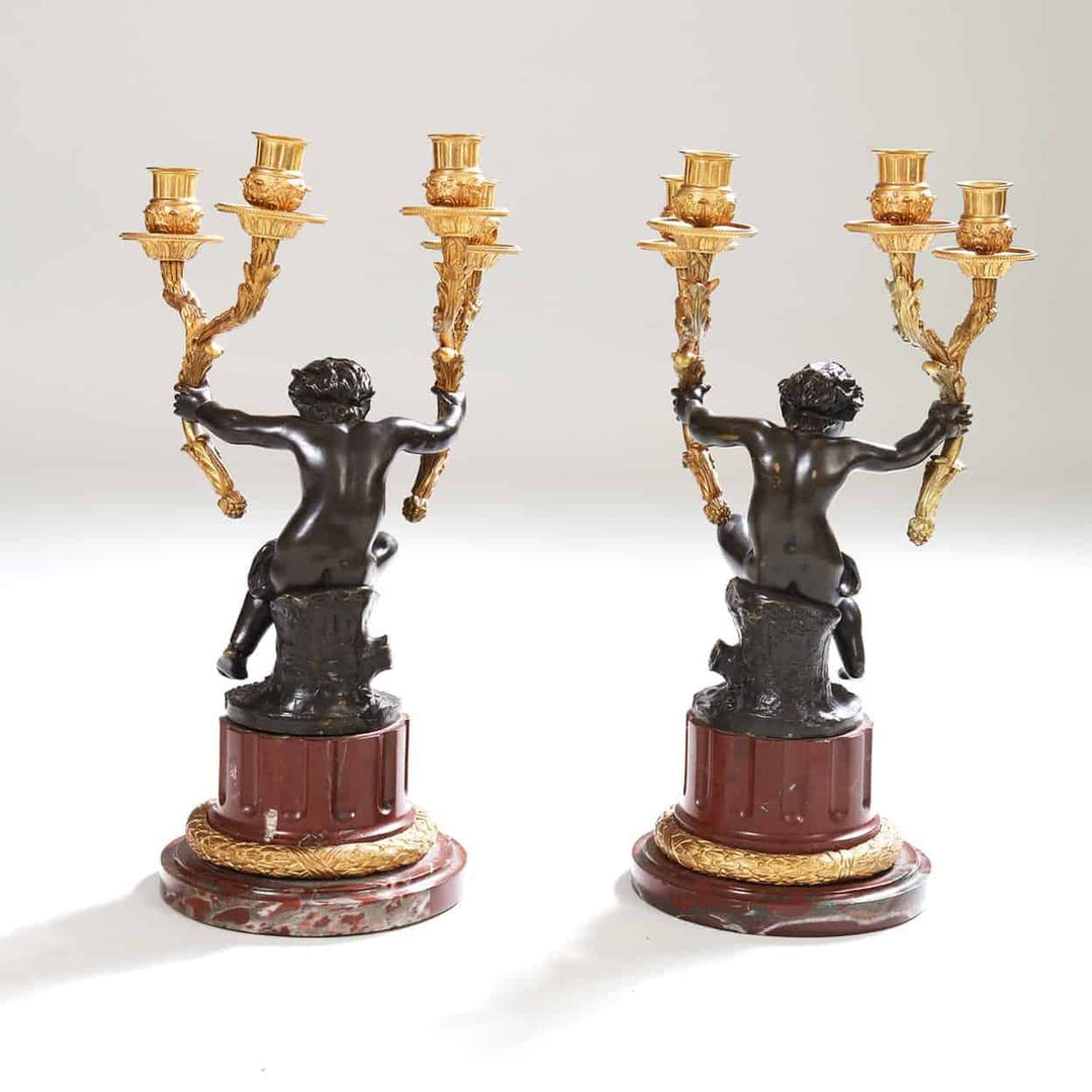 Pair of gilt bronze candelabra with seated bronze putti on rouge marble bases by Nicholas Wells Antiques