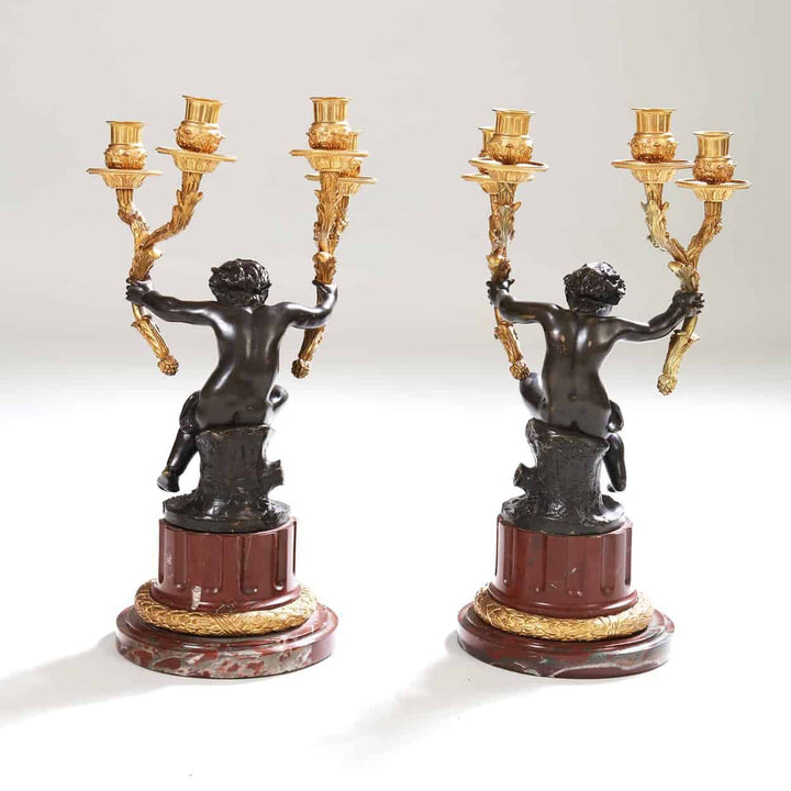 Pair of gilt bronze candelabra with seated bronze putti on rouge marble bases by Nicholas Wells Antiques