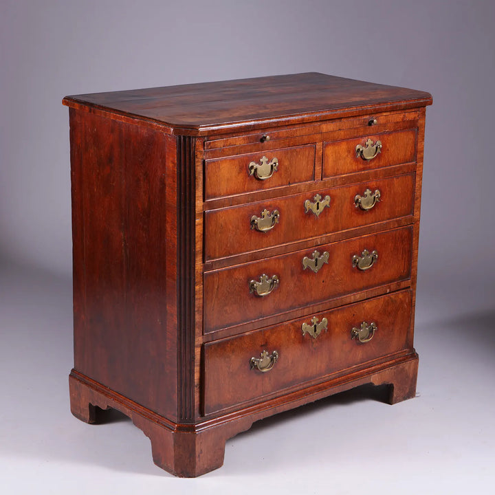 George I Walnut Chest of Drawers with feather banding, five drawers, fluted corners, and bracket feet, circa 1715-1720.