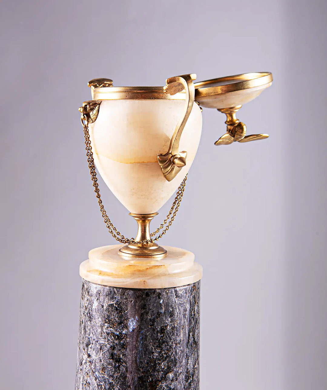Neoclassical Urn on Granite Pedestal with alabaster body, gilded bronze handles, lion’s head details, and bee finial.
