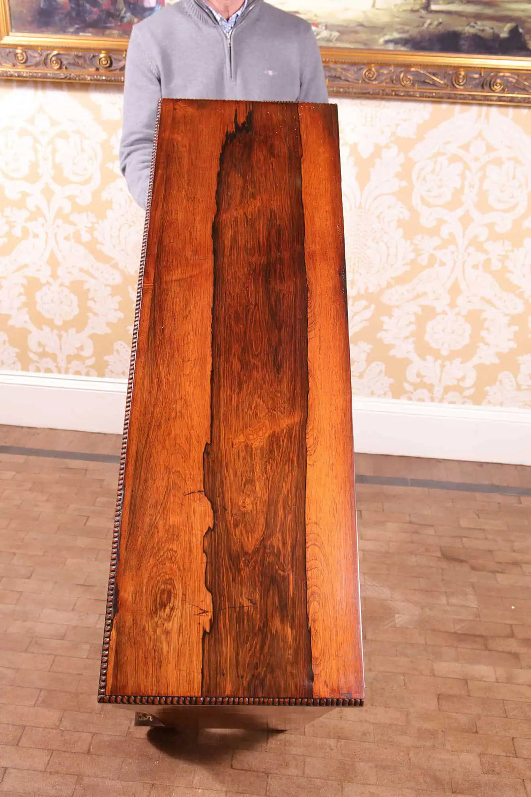 Person holding the polished rosewood top of a Regency side cabinet from Collection PK10 against classic wallpaper background