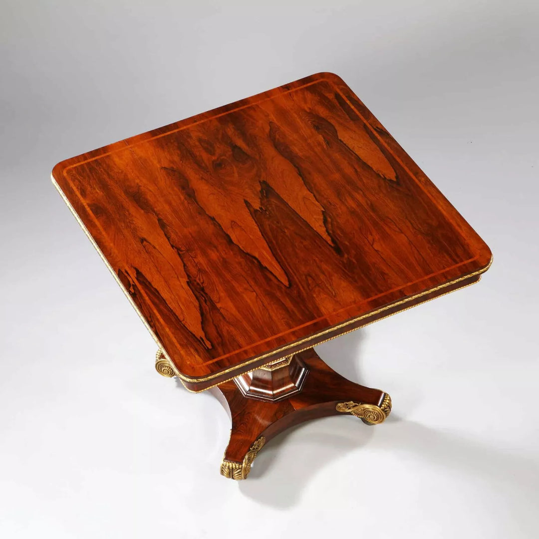 Regency Rosewood Square Center Table with bookmatched veneer, gilt metal edge, faceted base, and bronze feet, circa 1810.