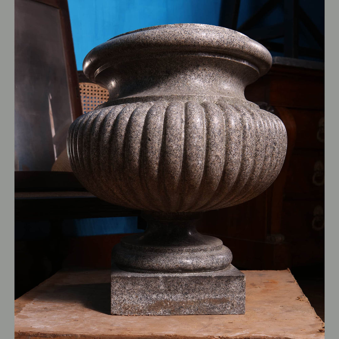 Large carved porphyritic granite gadrooned oval vase on stepped base from Collection EE20 displayed indoors