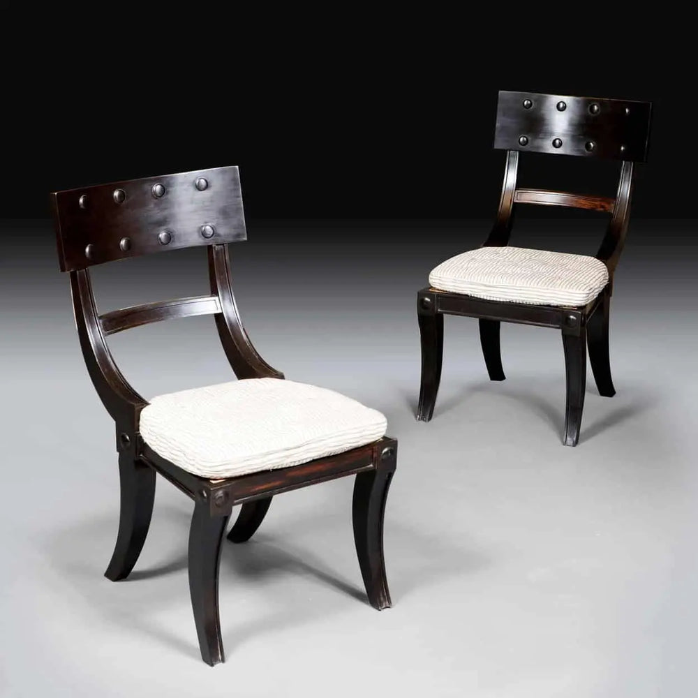 Two ebony Klismos dining chairs with curved legs and cushioned horsehair seats from Collection EE30