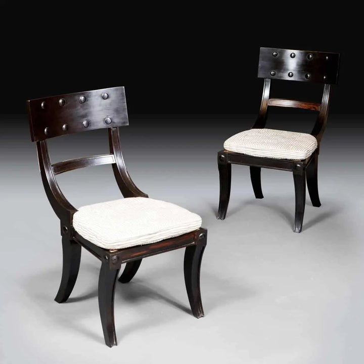 Two ebony Klismos dining chairs with curved legs and cushioned horsehair seats from Collection EE30