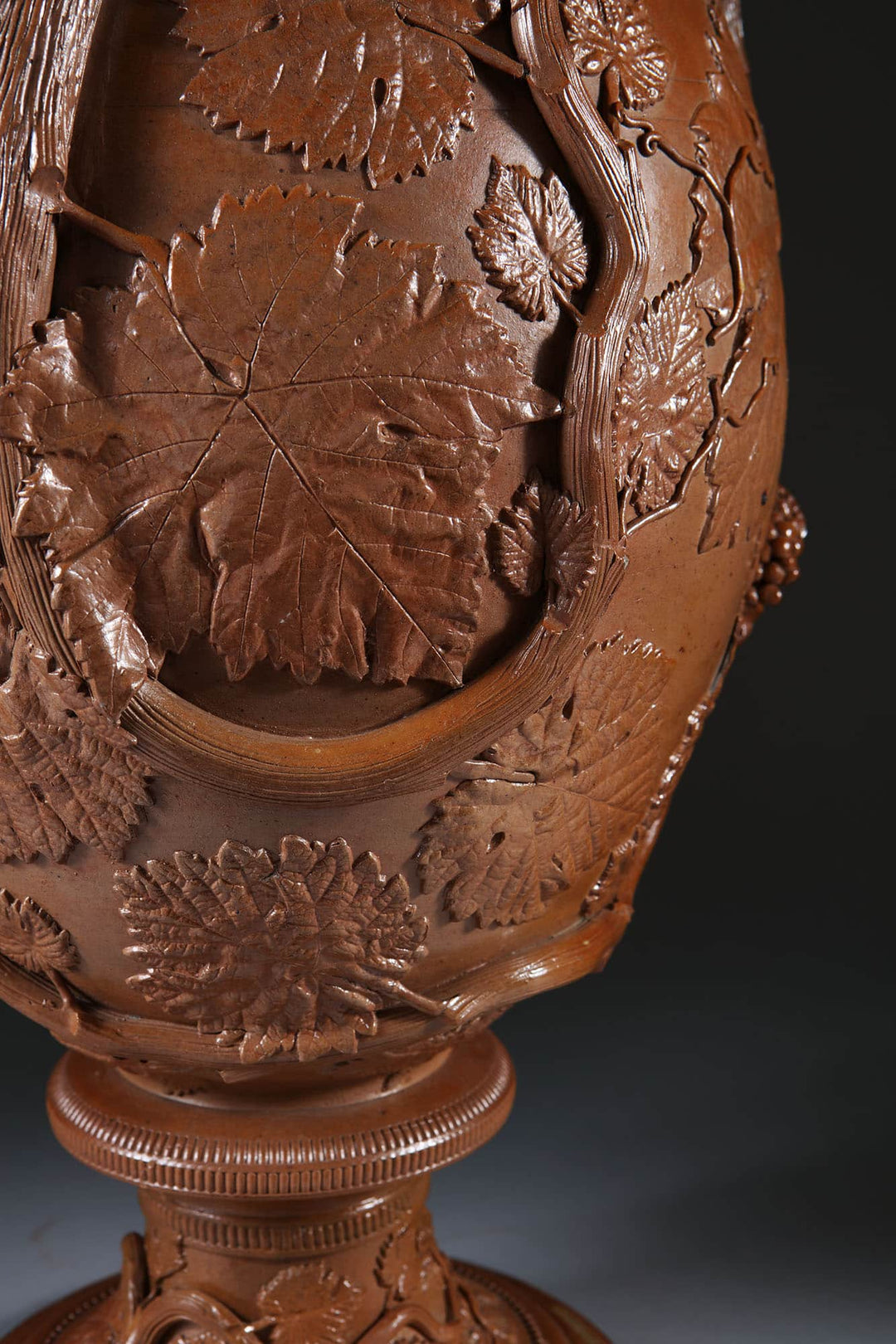Close-up of brown glazed stoneware vase with detailed leaf and vine design by Collection EE20