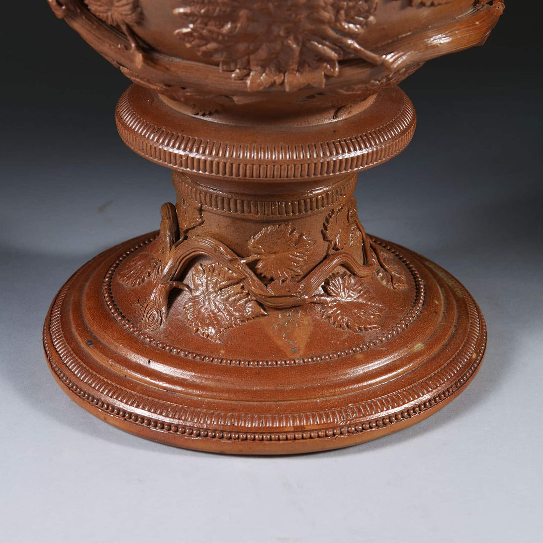 Detailed close-up of brown glazed stoneware vase base with ornamental leaf and vine design by Collection EE20