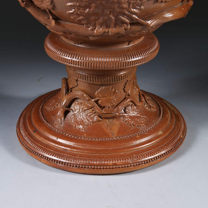 Detailed close-up of brown glazed stoneware vase base with ornamental leaf and vine design by Collection EE20