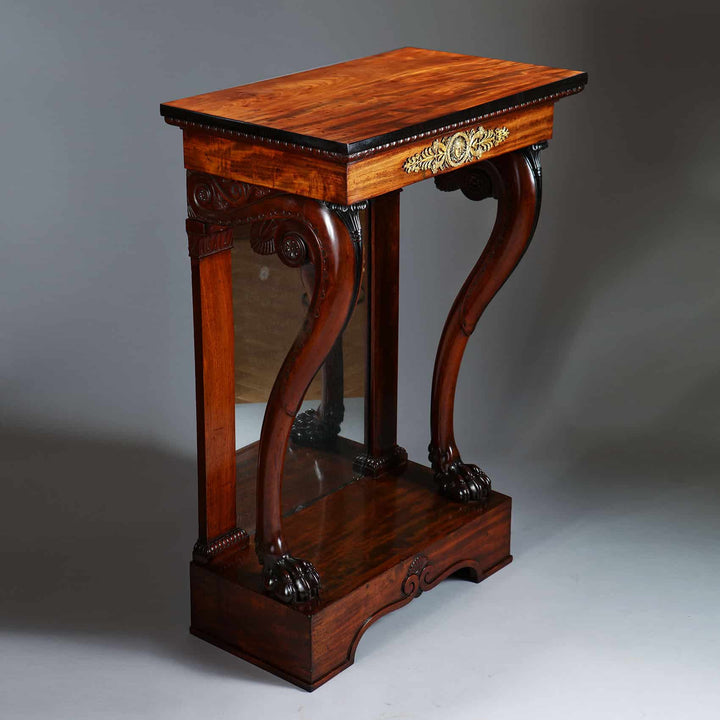Pair of Regency Pier Console Tables with mahogany top, ebony sides, gilt bronze mounts, carved lion feet, and inset mirrored backs.