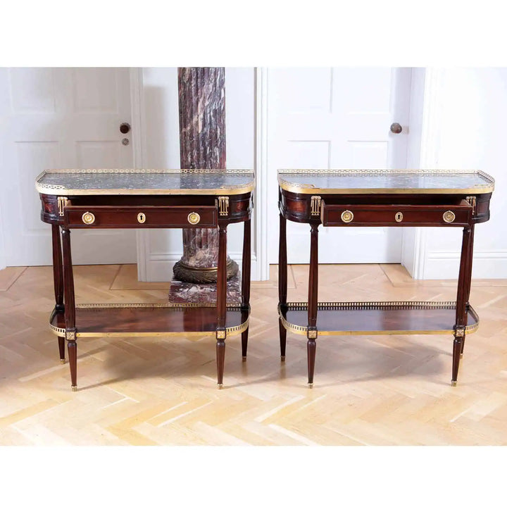 PAIR LOUIS XVI MAHOGANY CONSOLE DESSERTS with grey marble tops, brass galleries, single drawers, and fluted column legs.