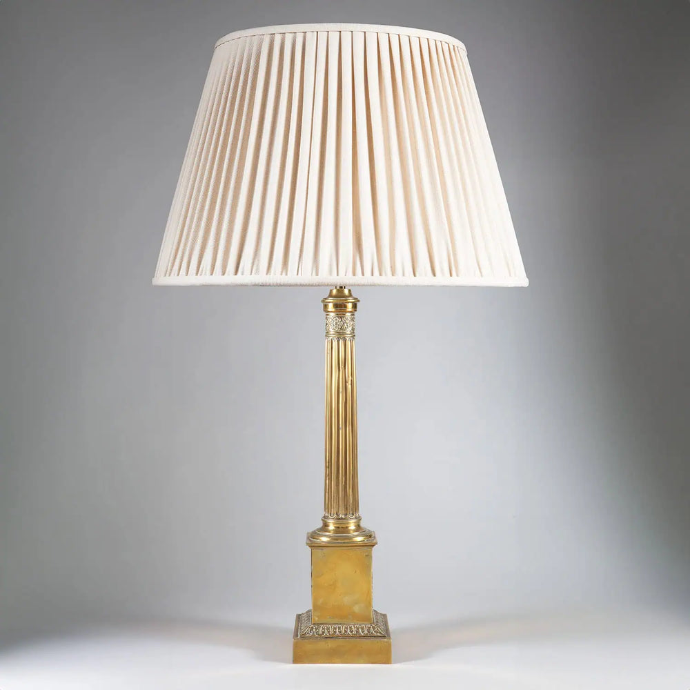 Fluted Brass Column Lamp with a fluted brass column and stepped base featuring foliate details and a pleated cream lampshade.