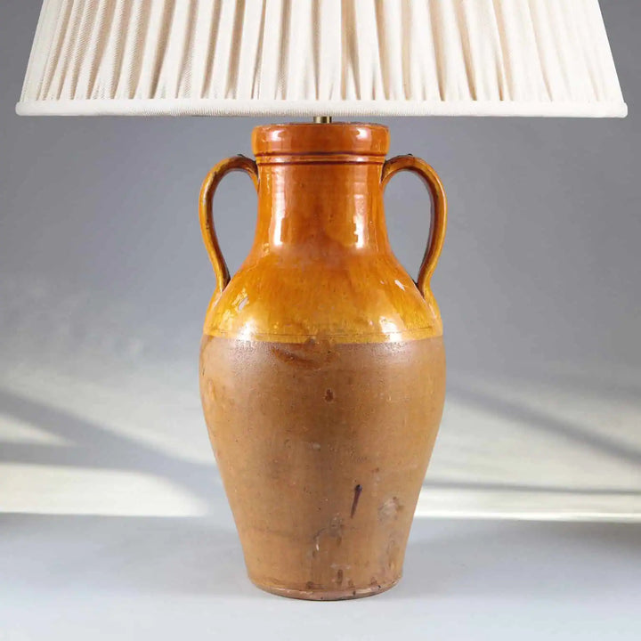 Yellow Umber Glazed Amphora Vase Mounted as a Table Lamp featuring a rustic yellow umber glazed amphora base with loop handles.