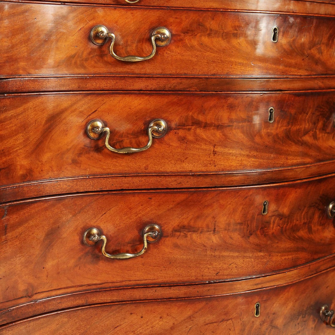 Fine George III Chippendale Chest Of Drawers with flame mahogany veneer and original gilt swan-neck handles.