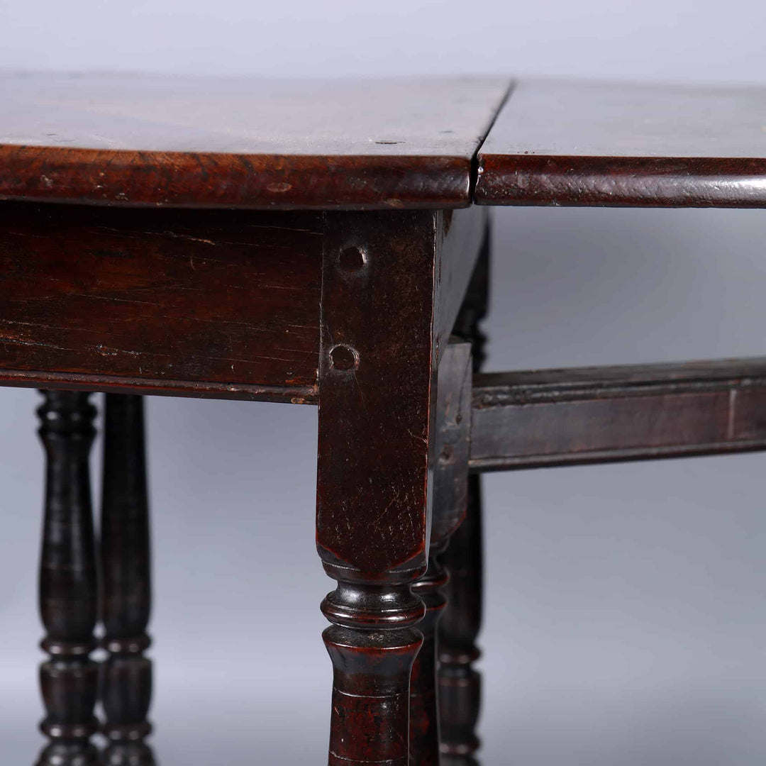 17th Century Oak drop leaf table with turned legs and stretchers, featuring elm top and oak drop leaves.
