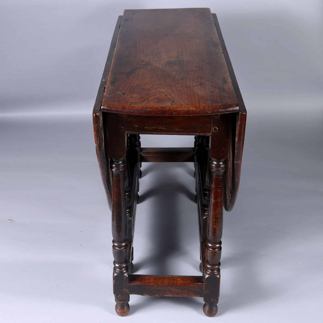 17th Century Oak drop leaf table with dark wood finish, turned legs, and foldable leaves, England 17th century.