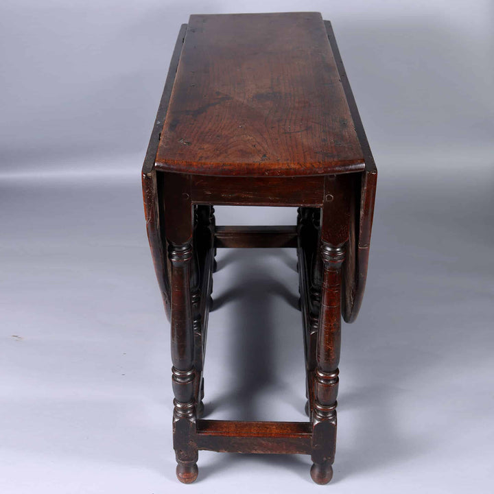 17th Century Oak drop leaf table with dark wood finish, turned legs, and foldable leaves, England 17th century.