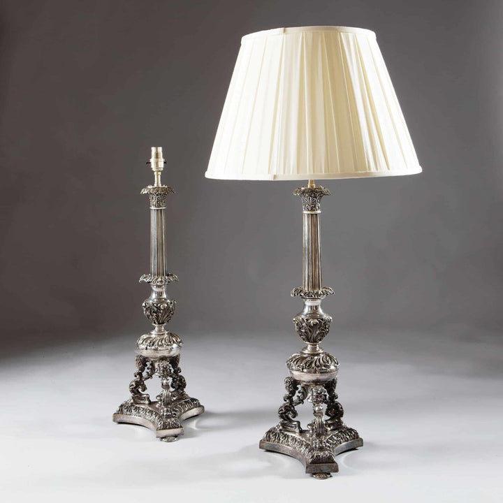 Pair Of Large Silvered Column Lamps Neo Renaissance silver plate design with intricate grotesque details and cream lampshade.