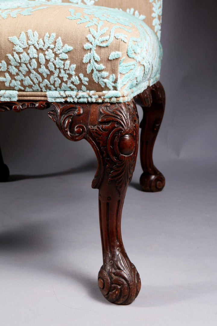 Close-up of mahogany chair leg with intricate carving and elegant upholstery from Collection CK20