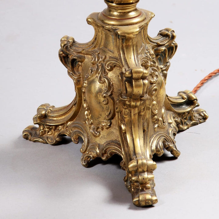 Pair of Brass Column Lamps with ornate detailed bases in vintage baroque style and a gold finish on a gray surface.