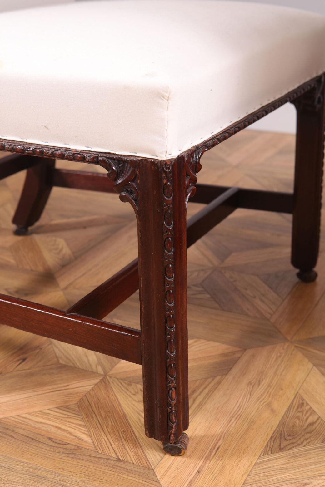 Close-up of George III mahogany side chair leg with carved details and white upholstered seat by Collection CK20