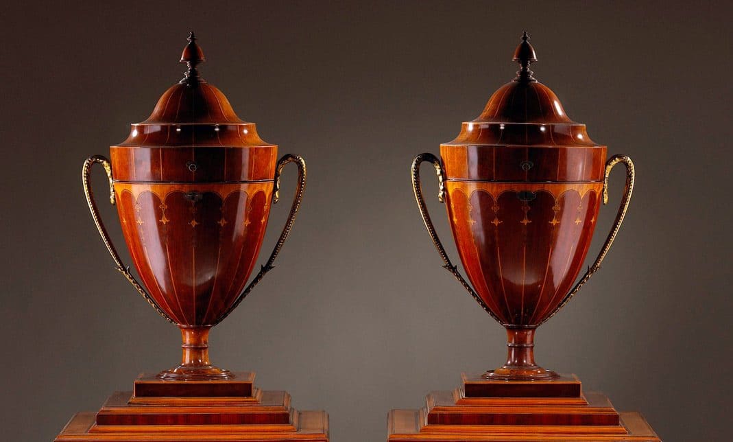 Pair of George III Sheraton Knife Urns on Stands, late 18th century English wooden urns with decorative brass handles.