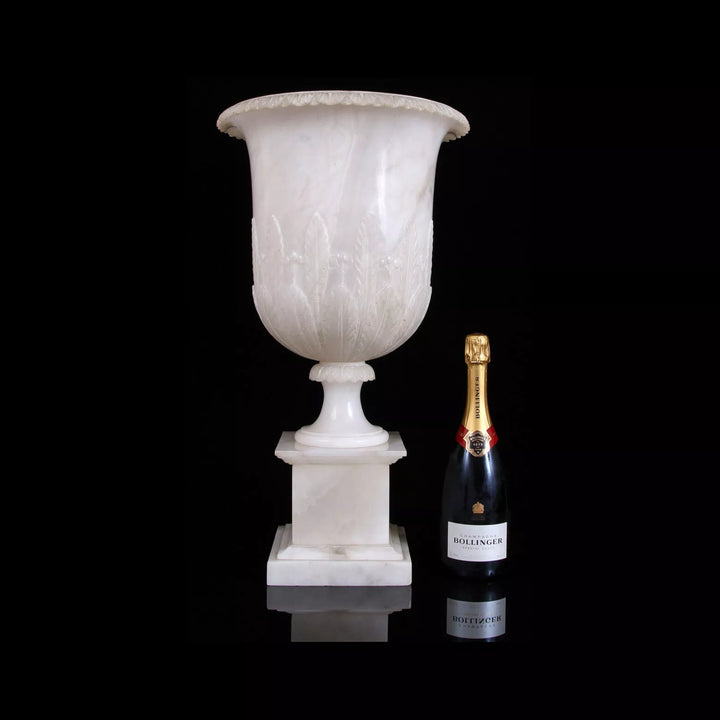Neoclassical Alabaster Vase on stand with detailed carvings, illuminated design, England circa 1900, shown with champagne bottle.