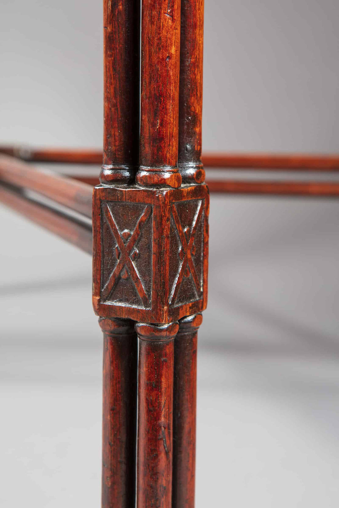 A close-up of the cluster column leg with cruciform ornament on the George III mahogany silver table.