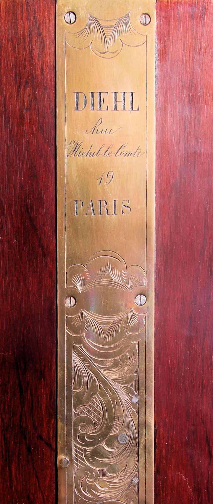 Close-up of engraved brass plaque on mahogany furniture by Diehl, showcasing Parisian craftsmanship, Collection CK20.