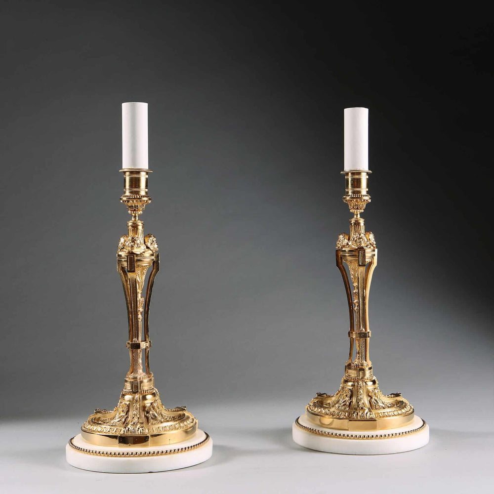 Pair of French Gilt Bronze Neo Classical Candlestick Table Lamps with white marble bases and gilt bead borders.