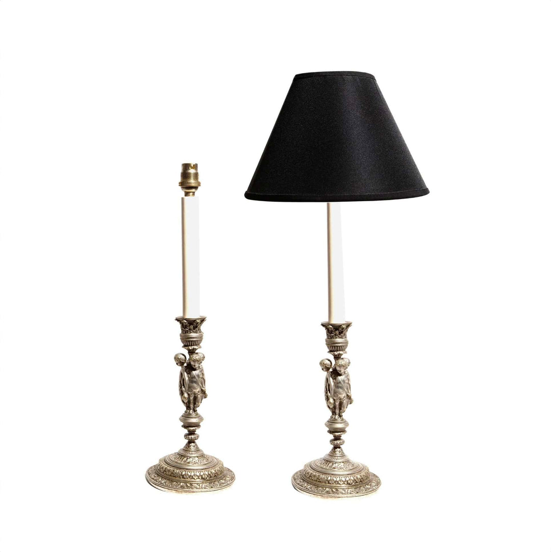Pair of Silvered Putti Table Lamps with cherub figures on ornate bases, one with black shade, circa 1850, France.