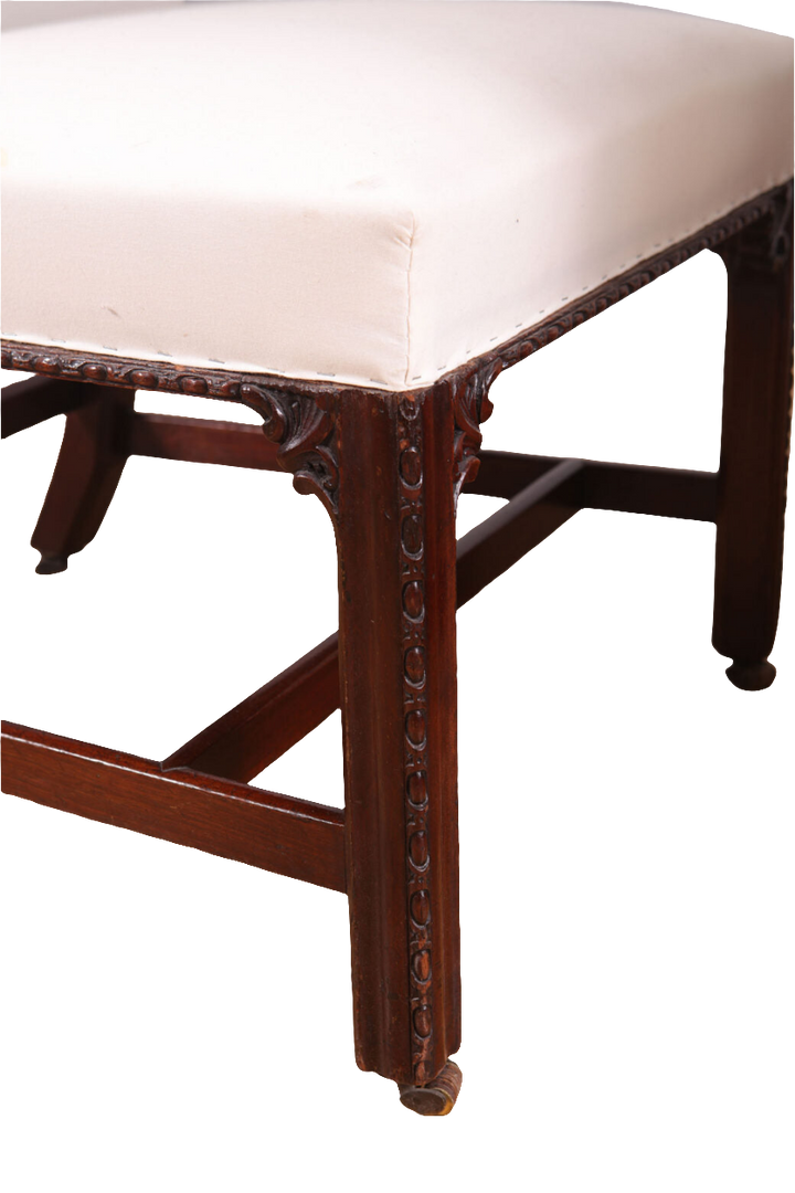 Close-up of a George III mahogany side chair leg with detailed carving and white upholstery by Collection CK20