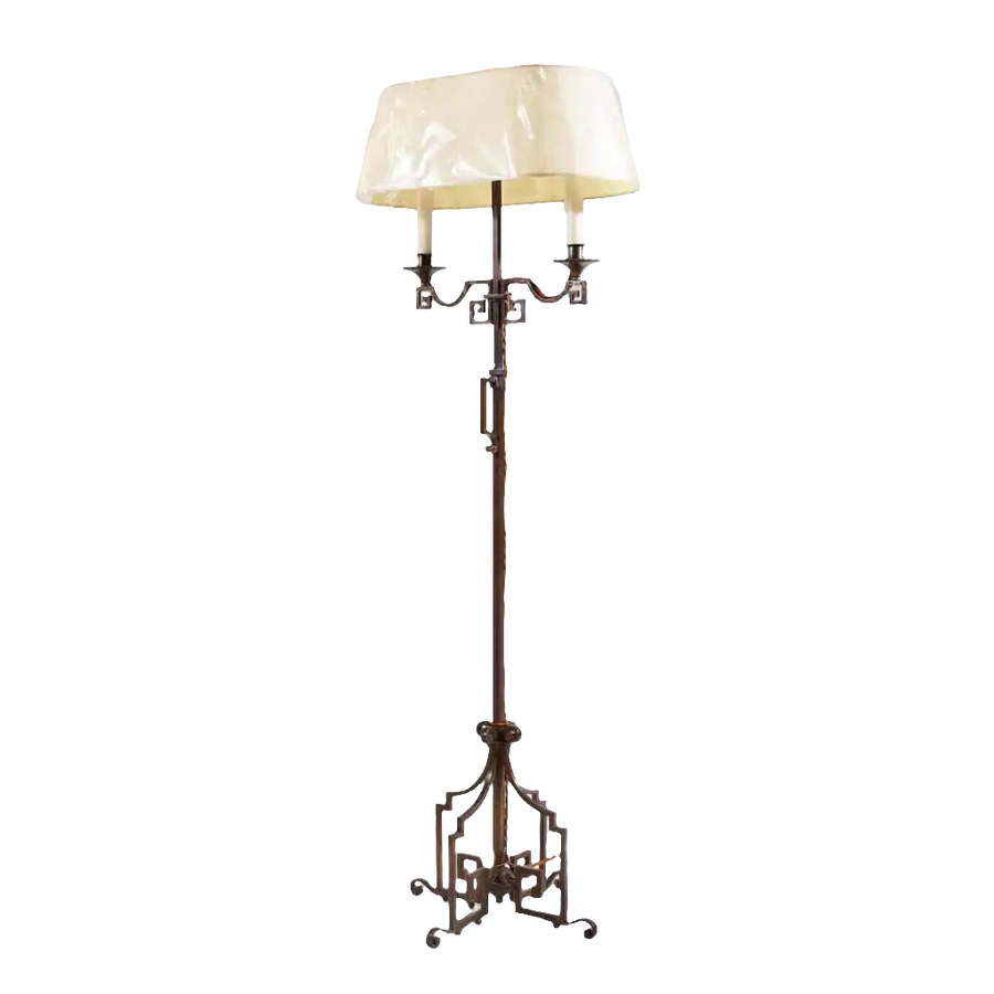 A patinated Steel floor standing bouillotte lamp with key scroll base and adjustable two-branch shaded light, circa 1920.