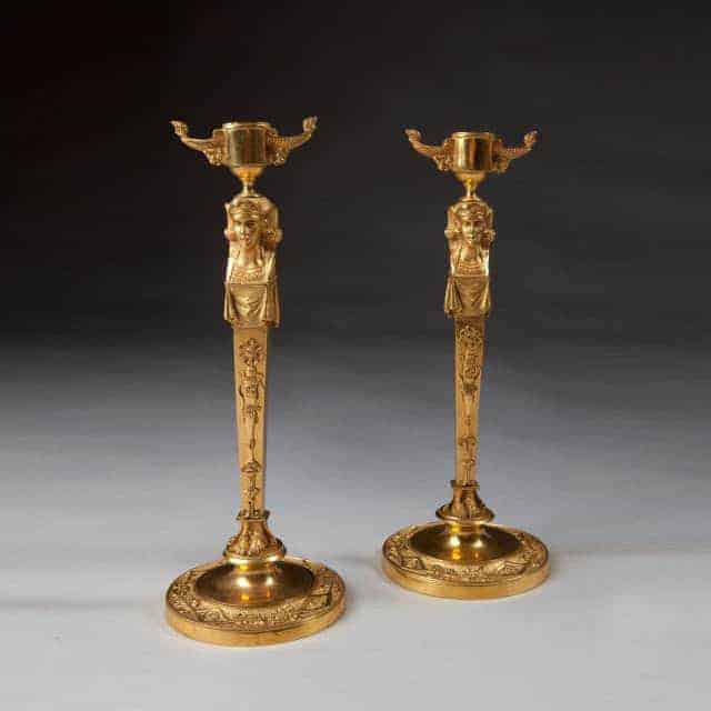 Pair Of Neo Egyptian Empire Gilt Bronze Candlesticks with female caryatid figures and lion mask handles, circa 1820.