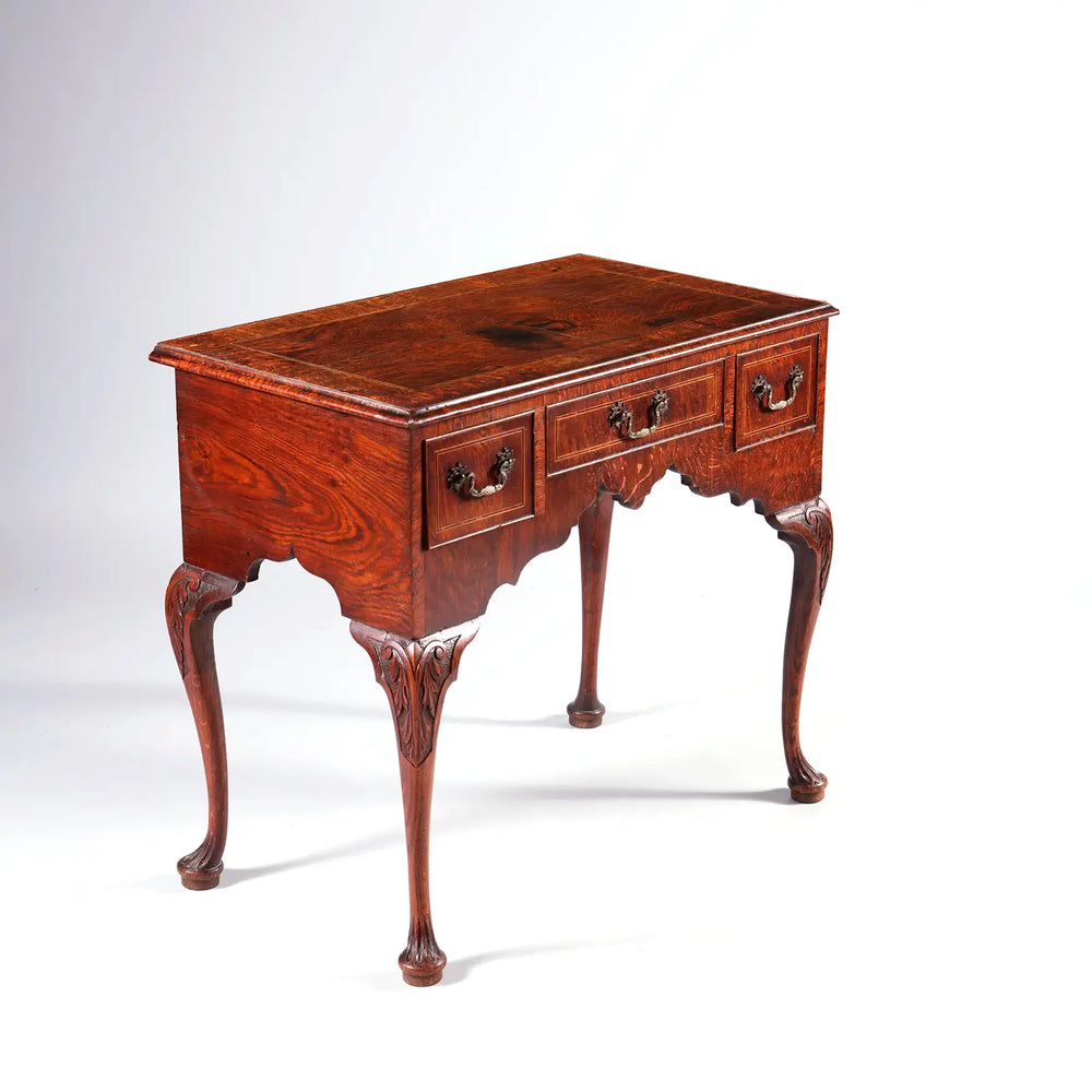 GEORGE II OAK LOW BOY with three drawers, cabriole legs, and carved foliate details, English 18th century style.