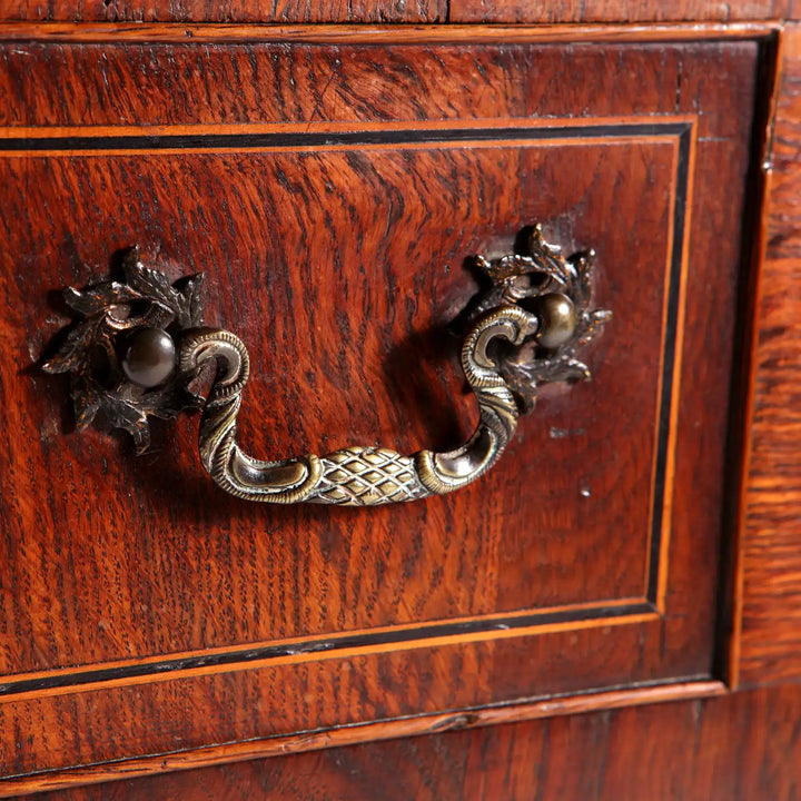 GEORGE II OAK LOW BOY drawer handle detail with intricate brass drop handles and oak veneer paneling.