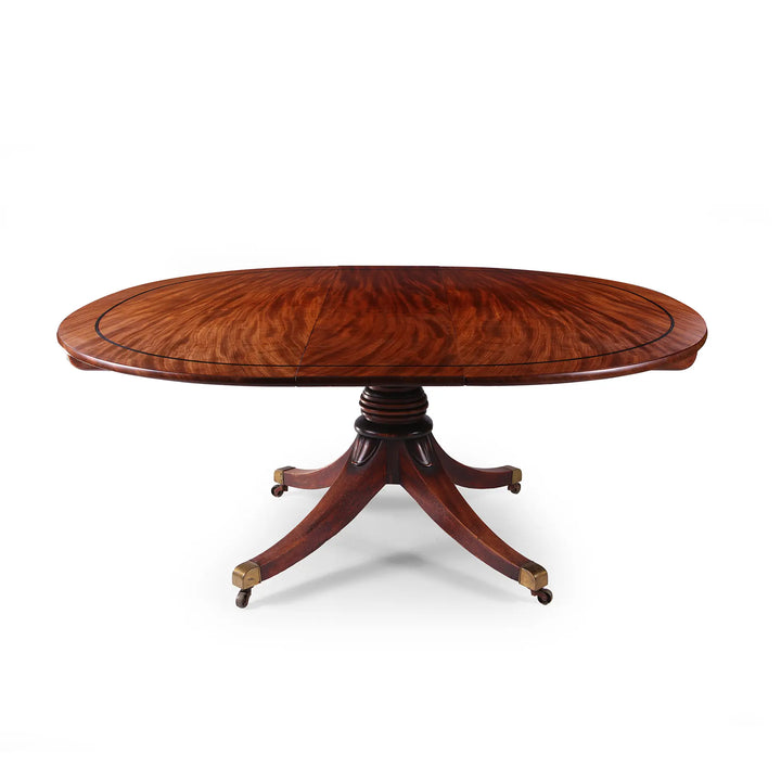 Extending Oval Dining Table in the Manner of George Bullock with mahogany top and pedestal base on cast brass castors.