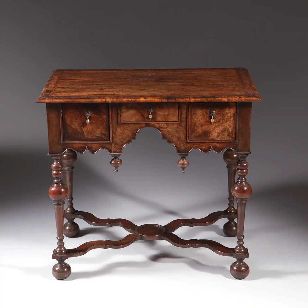 GEORGE I WALNUT LOW BOY with three drawers, Dutch gable aprons, lathe turned legs, and bun feet, circa 1700 England.