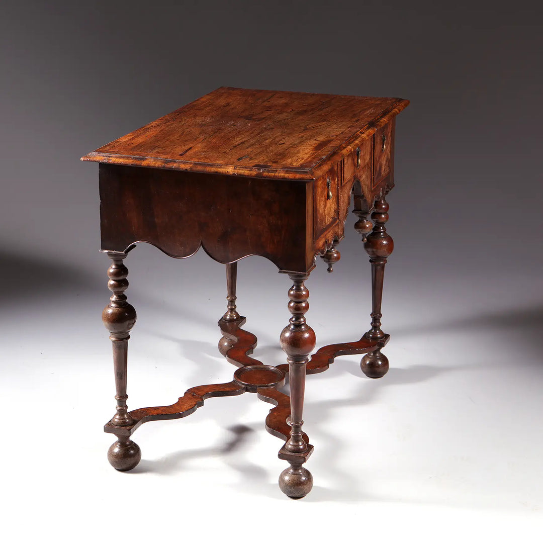 GEORGE I WALNUT LOW BOY with rectangular top, Dutch gable aprons, lathe turned legs, X stretcher, and bun feet circa 1700.