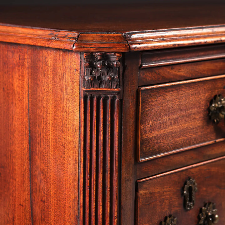 GEORGE II MAHOGANY KNEEHOLE DESK detailed corner with fluted column and brass drawer handles.