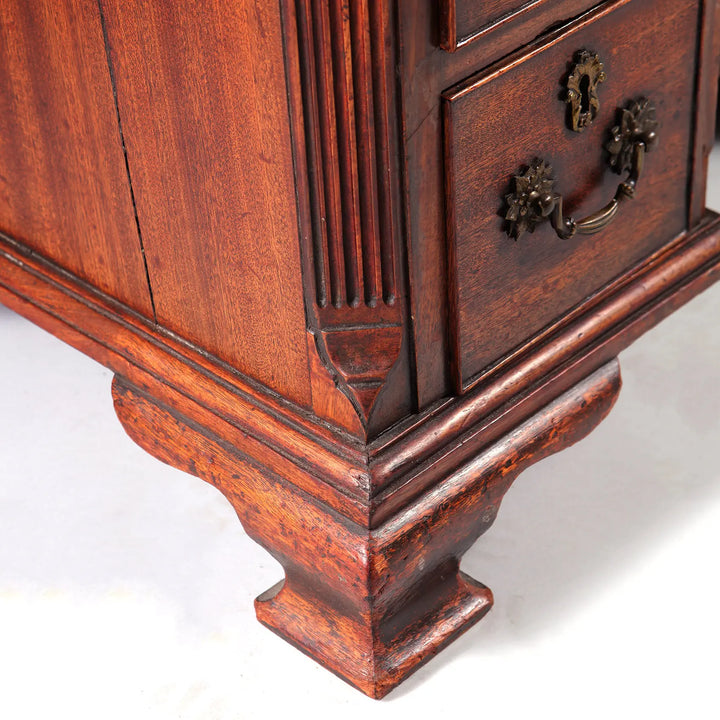 GEORGE II MAHOGANY KNEEHOLE DESK close-up of ogee bracket foot and detailed wood grain in mahogany finish.