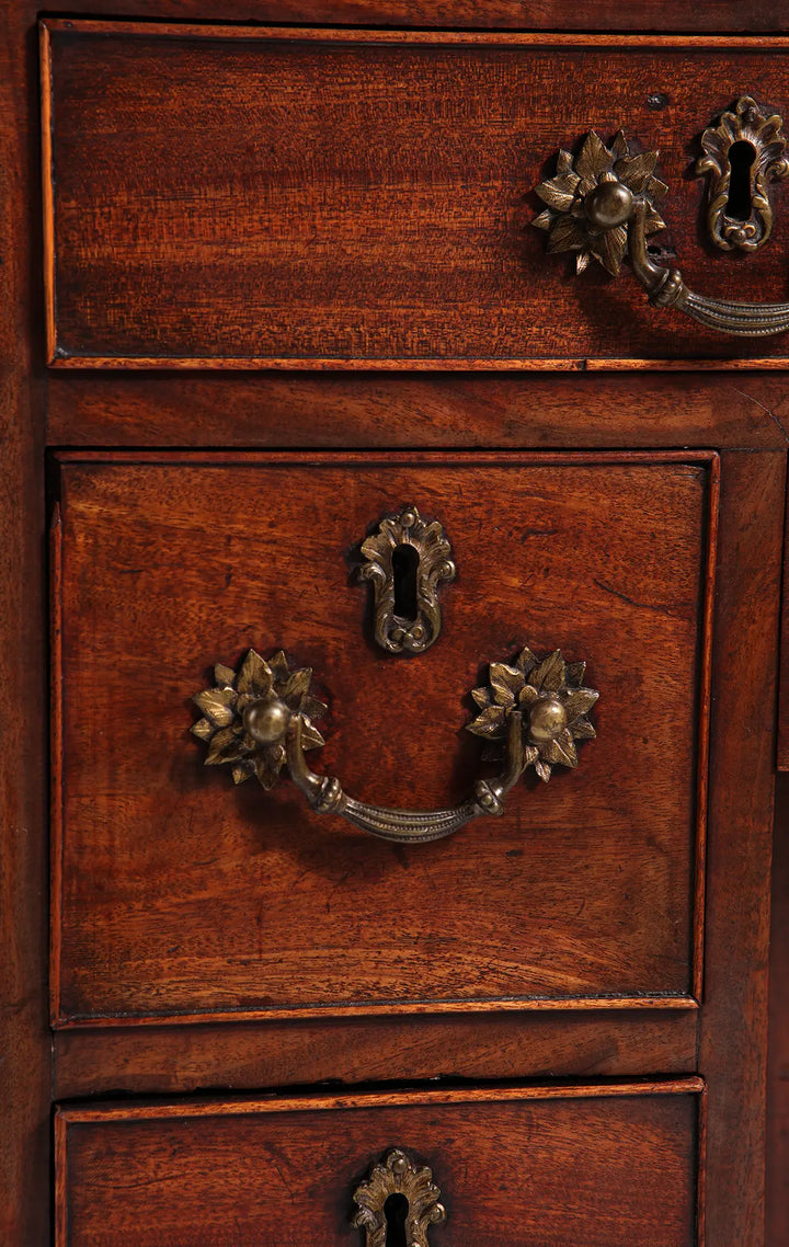 GEORGE II MAHOGANY KNEEHOLE DESK close-up of brass handles and keyhole on finely figured mahogany drawers.