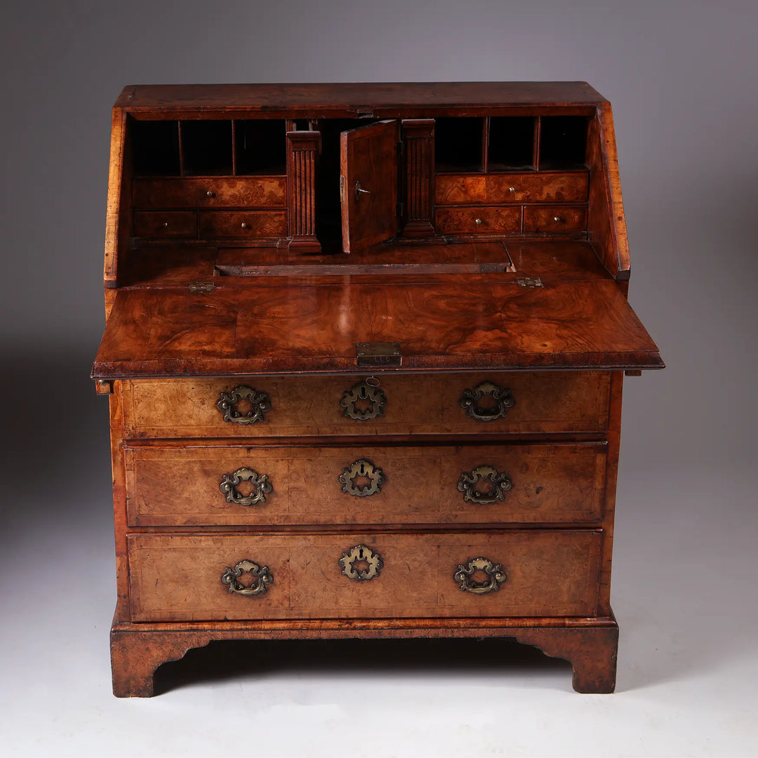GEORGE I BURR WALNUT BUREAU CHEST with fall front, brass handles, secret compartments, and figured burr walnut finish.