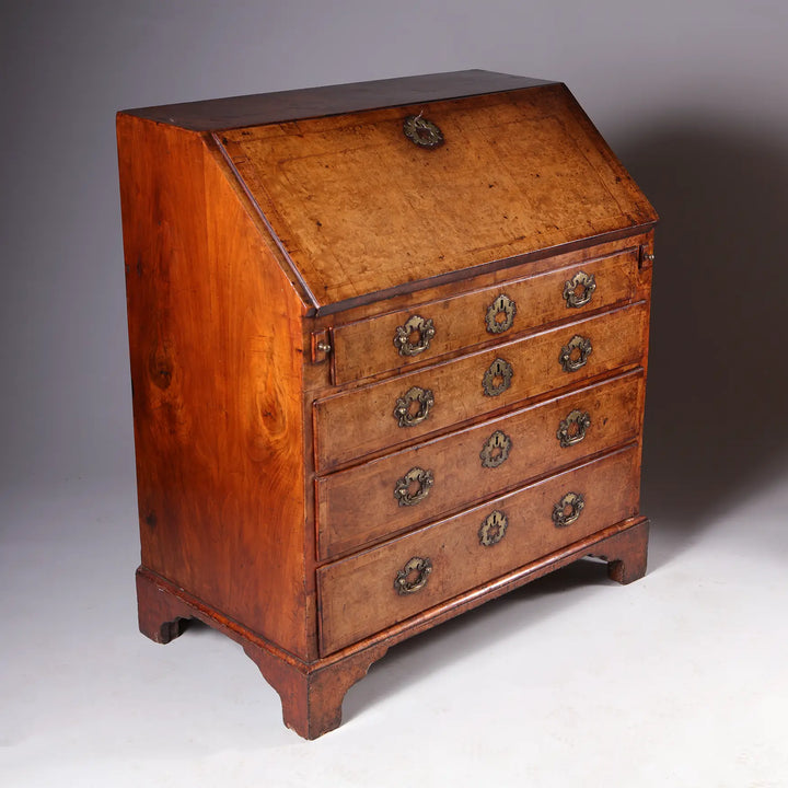 GEORGE I BURR WALNUT BUREAU CHEST with fall front, brass handles, and four graduated drawers in honey patina finish.