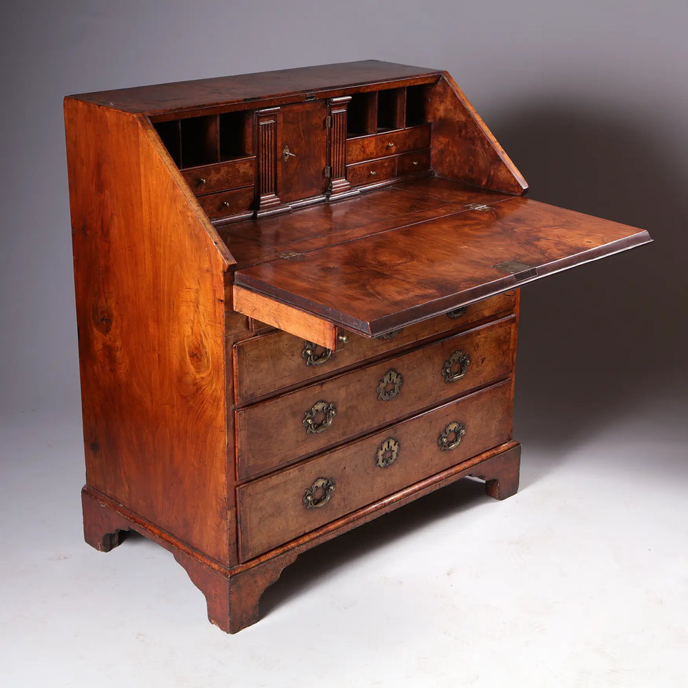 GEORGE I BURR WALNUT BUREAU CHEST with fall front, brass handles, secret compartments, and figured walnut finish.