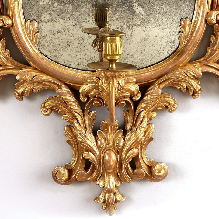 Georgian giltwood girandole mirror with carved anthemion, acanthus leaves, and single candle arm, England circa 1780.