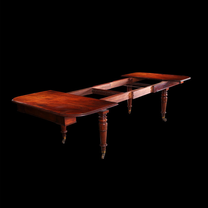Extending Antique Dining Table in Flame Mahogany partially extended with detailed turned legs on black background.