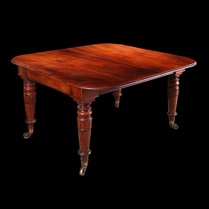 Extending Antique Dining Table in Flame Mahogany with turned legs and rich wood grain on a dark background.