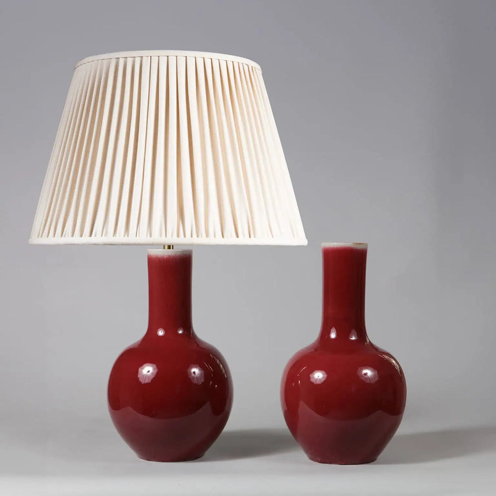 Pair of Ox Blood Glazed Porcelain Bottle Vases as Table Lamps with one lamp and one vase on a gray background